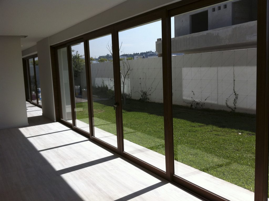 Fachada de casa con marcos de ventana corrediza de madera a medida