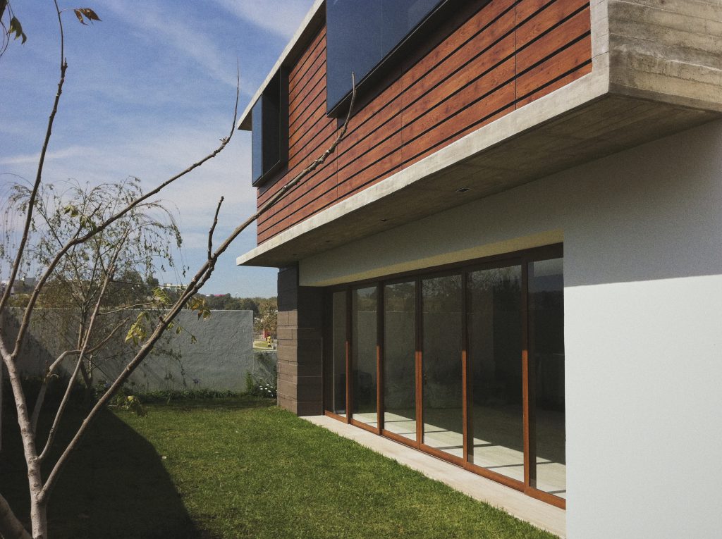 Fachada de casa con marcos de ventana corrediza de madera a medida